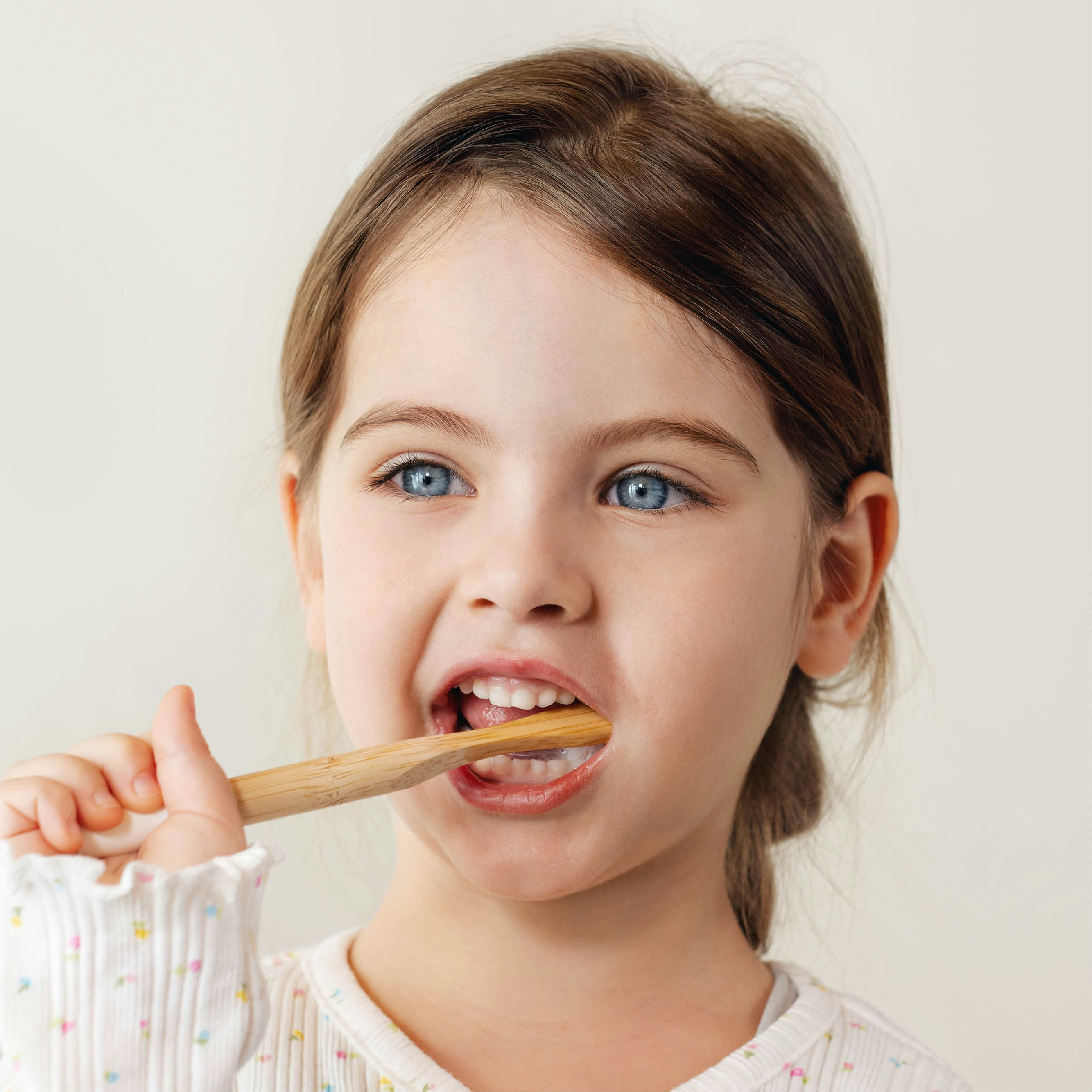 Abgebildet ist ein kleines Mädchen, welches sich mit dem FRESH baby tooth gel ihre Zähne putzt. Sie benutzt dabei eine nachhaltige Zahnbürste.